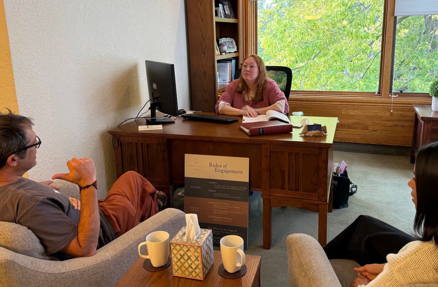 A mediation session in progress at the Conscious Family office, two people seated across from an attorney-mediator.